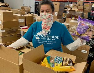 Volunteer helping pack nonperishable food into a box for New Mexico families in need at the Storehouse food pantry