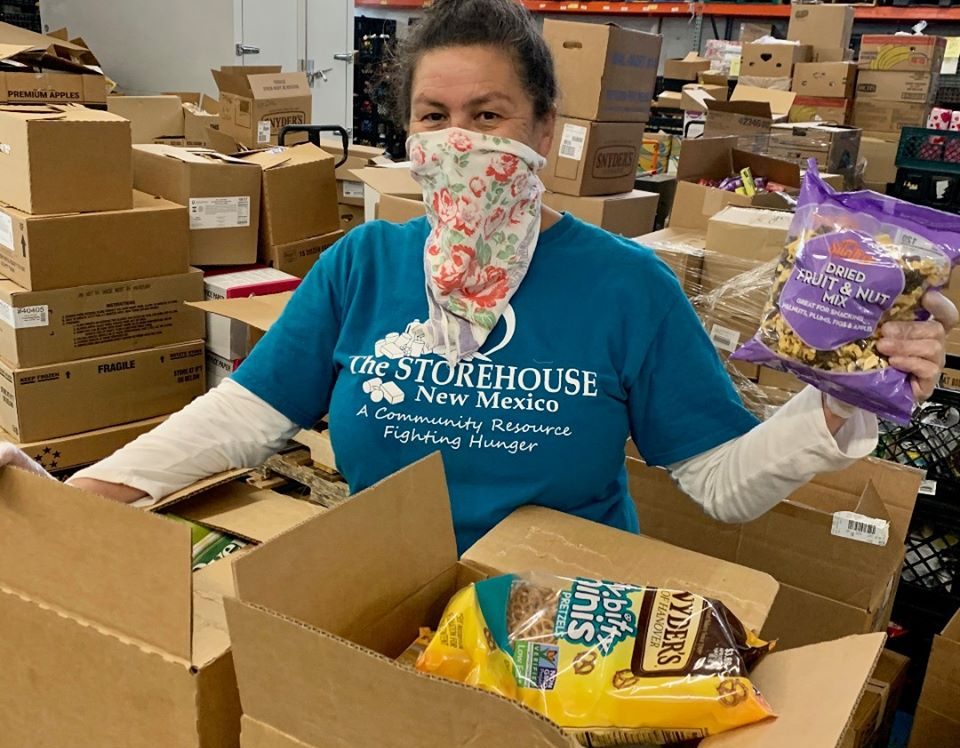 This wonderful volunteer is helping pack up boxes. She is wearing a scarf over her nose and mouth.