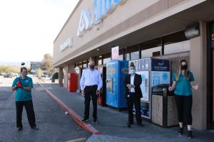 Albertsons managers pose with golf items and a donation in front of Albertsons Market store