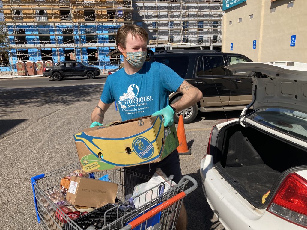 A Storehouse employee loads food up in a car for a family. When you donate to our food panty, you help feed our neighbors. 