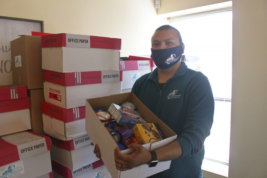 Staff Member Tim holds a box of food for a family. He is wearing a mask. Our local churches helped with staffing by raising money for Tim's salary! 