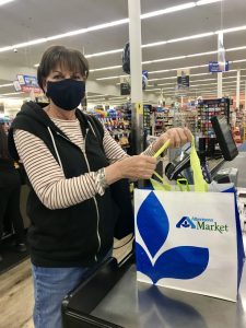 woman smiles after checking out at the Albertsons Market with her groceries