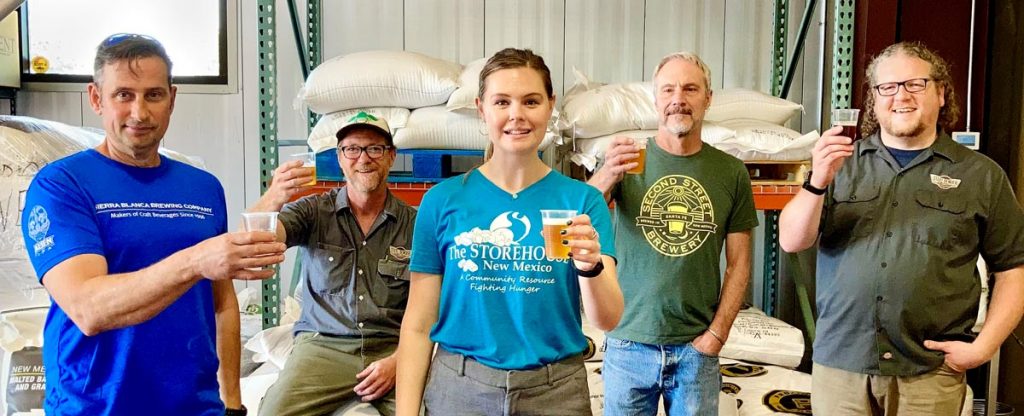 Brewers from Sierra Blanca Brewing Company, Steel Bender Brewyard, and Second Street Brewery toast the new One for 5 hazy pale ale beer they brewed together to raise money for the Storehouse of New Mexico.