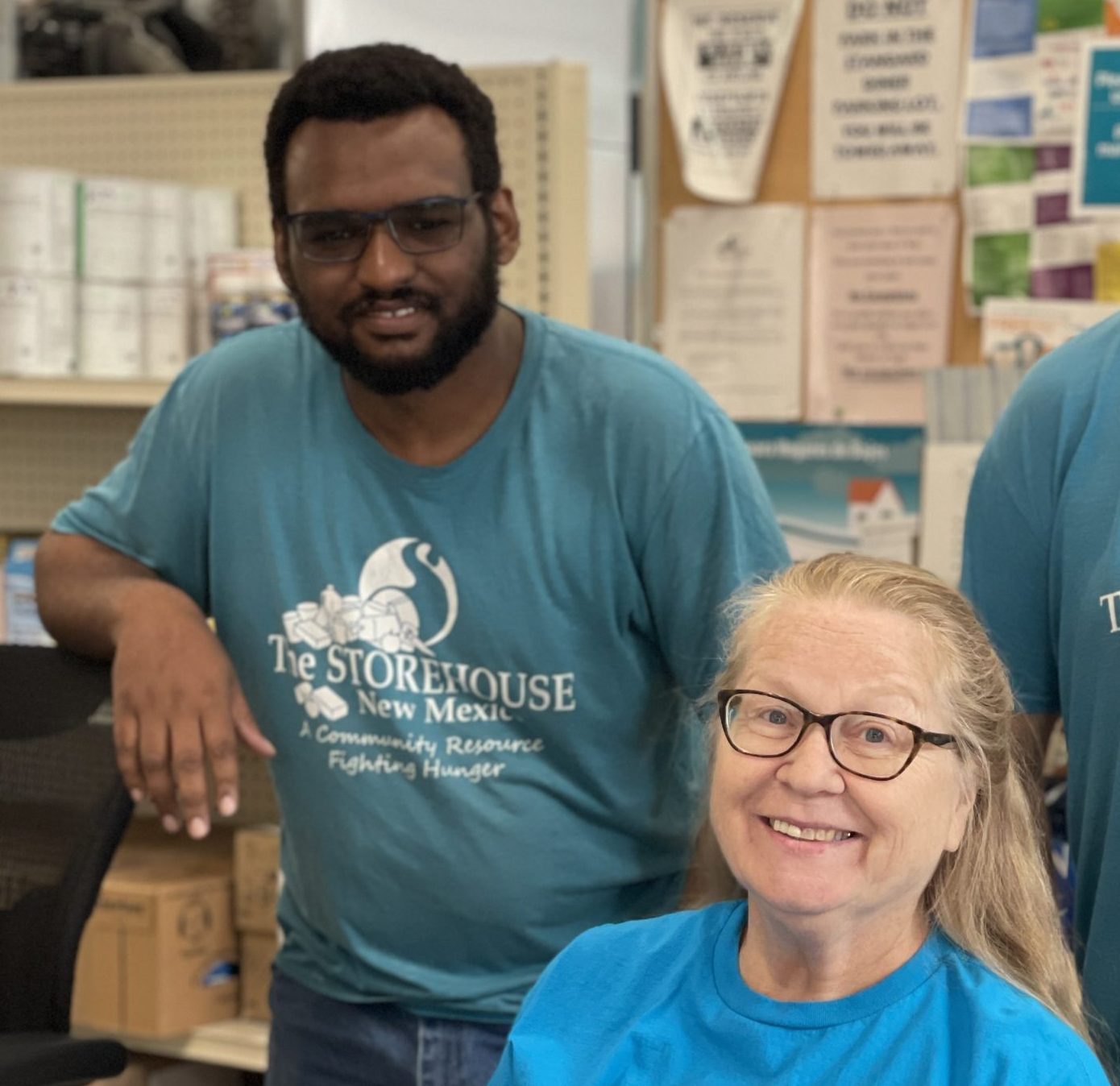 Volunteer helping pack nonperishable food into a box for New Mexico families in need at the Storehouse food pantry