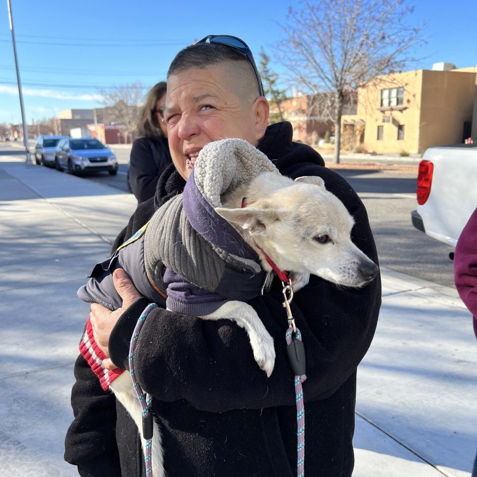 woman with her dog, both getting food at the Storehouse New Mexico food pantry. The pantry provides dog and cat food monthly.
