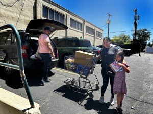 Members of a family loading groceries into their car in front of the Storehouse food pantry.  